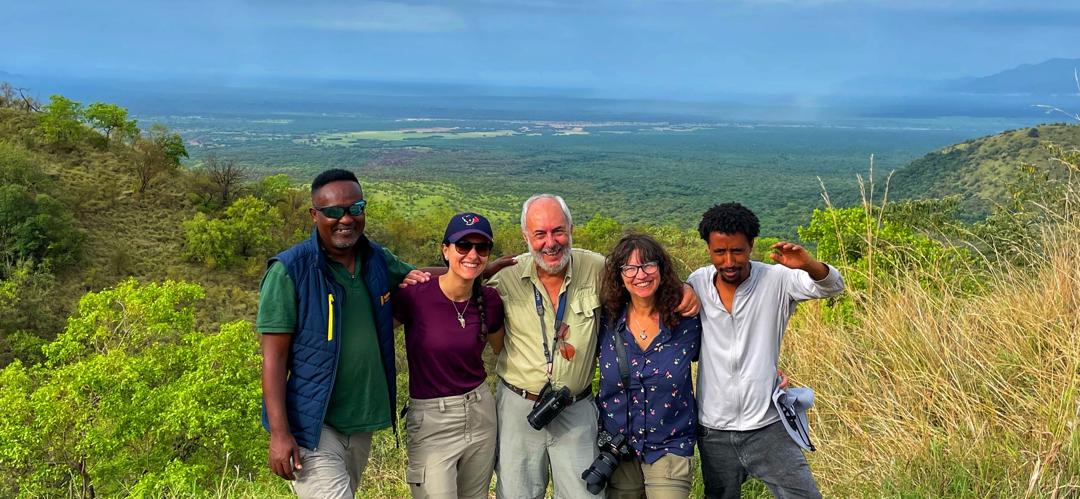 Group of tourists and local guides enjoying a scenic viewpoint over Omo Valley, Ethiopia during a cultural tour